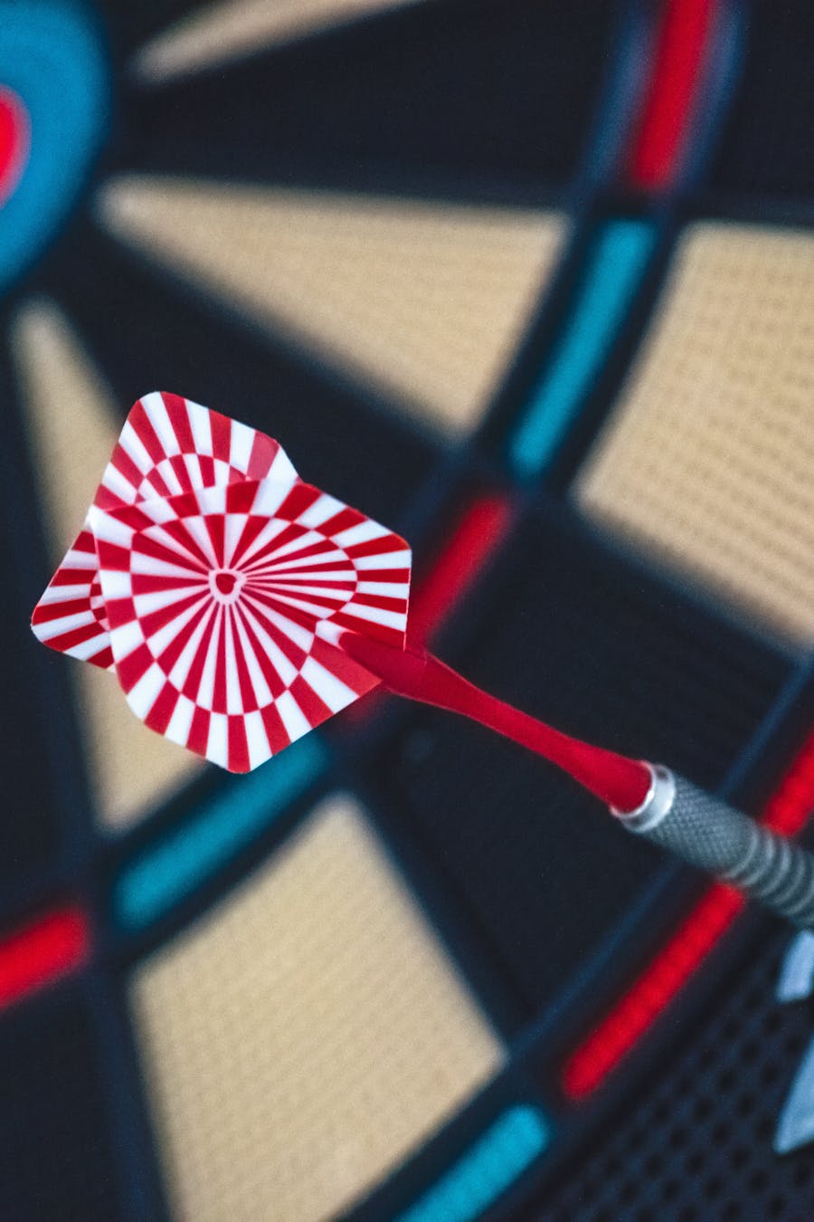 Close-up of a red and white striped dart on a colorful dartboard.